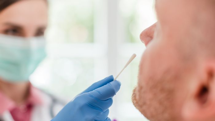 Doctor inserting swab in patients nose for Covid 19 test, close-up