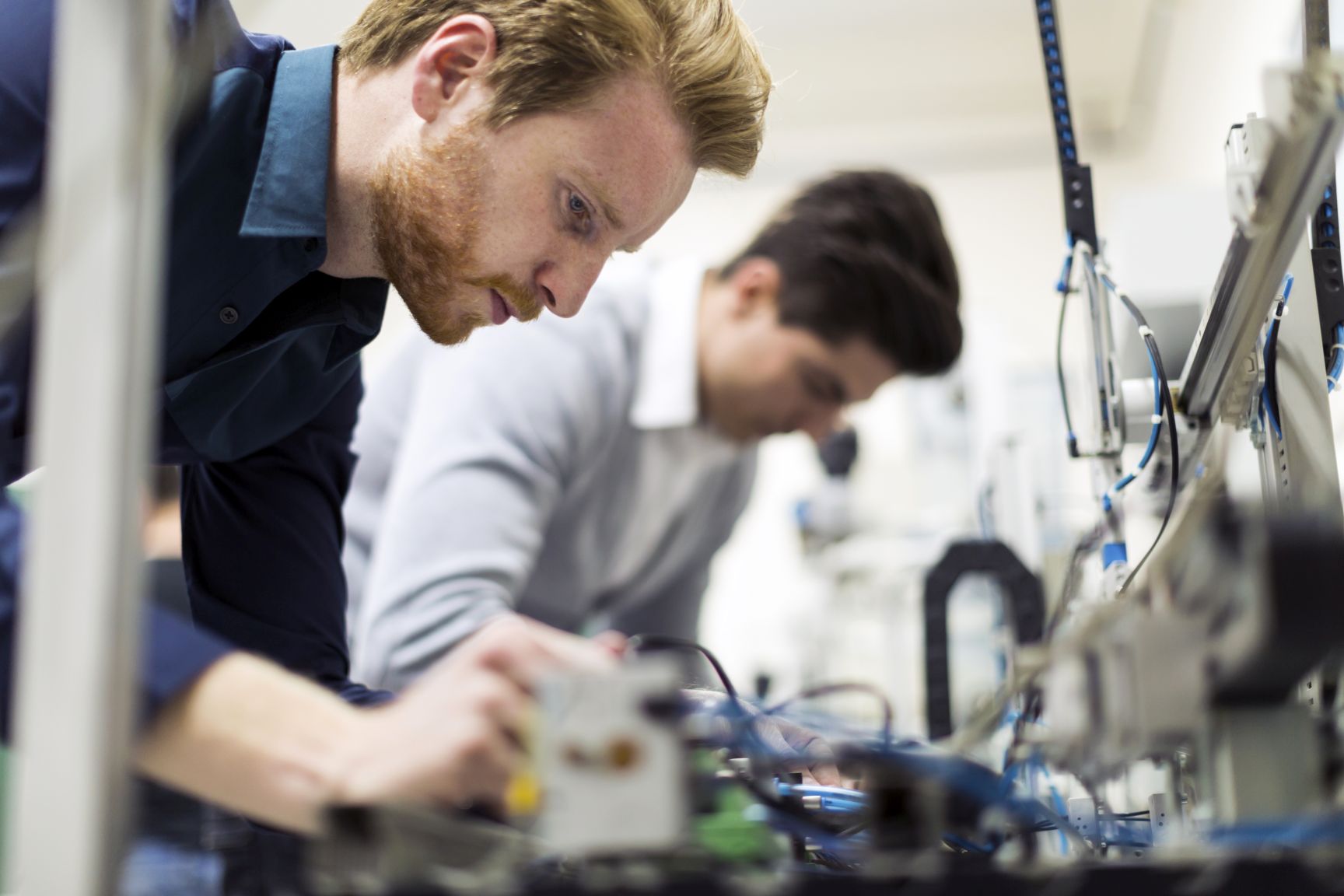 Two young handsome engineers working on electronics components and fixing broken chips