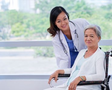 Pretty young doctor caring about elderly woman in wheelchair